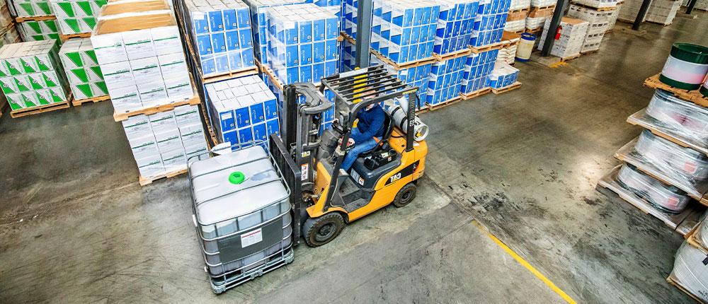 Forklift driving in warehouse full of boxes
